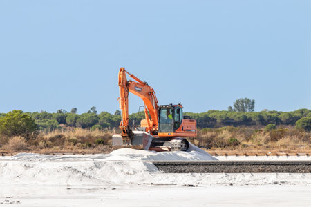 Huelva, Spain - October 1, 2020: Excavator working in salt production in nature reserve Marismas del Odiel. Traditional Sea salt production is salt that is produced by the evaporation of seawater.のeditorial素材