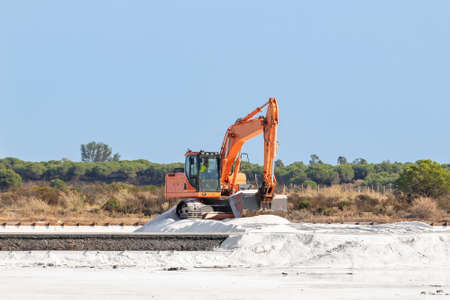 Excavator working in salt production in nature reserve Marismas del Odiel. Traditional Sea salt...