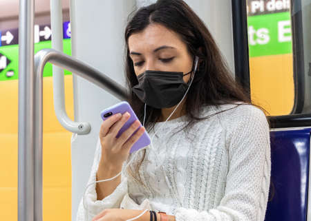 Barcelona, Spain - September 21, 2021: A young woman is using her mobile phone while is traveling in...