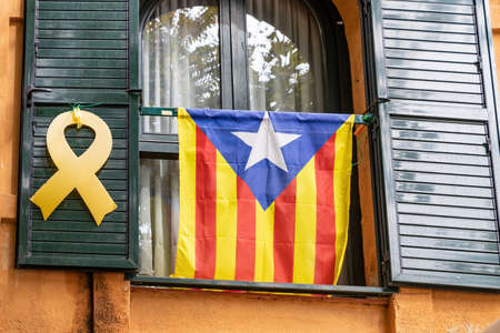 Catalan independence flag and yellow ribbon hanging from a window demanding the independence of Catalonia and the freedom of the imprisoned politiciansの写真素材