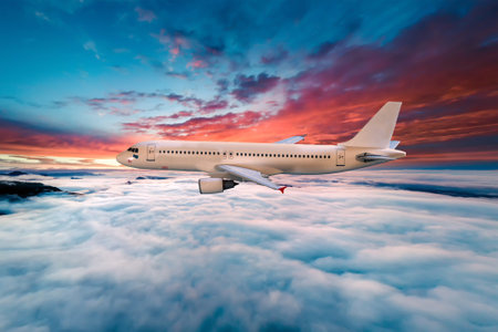 Airplane flying above the clouds at sunset