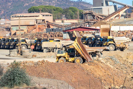 Mining trucks and machinery in Corta Atalaya open mine pit. Deep excavation of pyrite and extraction...