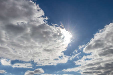 View of a cloudy sky with the sun peeking through the clouds for background