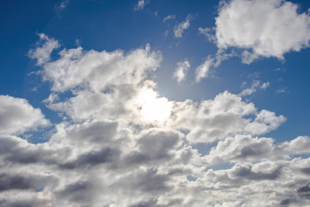 View of a cloudy sky with the sun peeking through the clouds for backgroundの写真素材