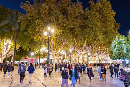 Seville, Spain - December 22,2020: Unidentified People walking around Seville City hall at christmas time. People wearing protective face mask due coronavirus covid-19のeditorial素材