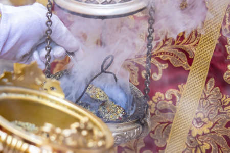 Detail of the hand of an altar boy or acolyte in a Holy Week procession filling one of the censers with incenseの写真素材