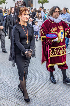 Huelva, Spain - April 15, 2022: A Woman with a black spanish mantilla and peineta (ornamental comb),...