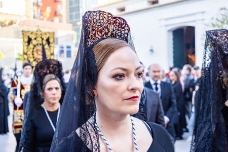 Huelva, Spain - April 15, 2022: A Woman with a black spanish mantilla and peineta (ornamental comb),...