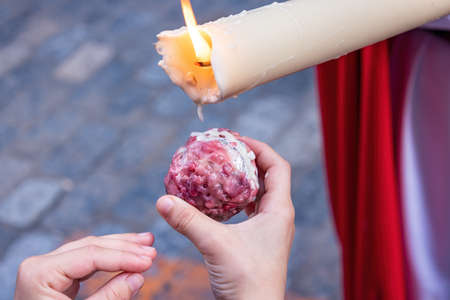 Close Up of the hand of a girl kid collecting wax for his wax-ball during the Holy Week procession.の写真素材