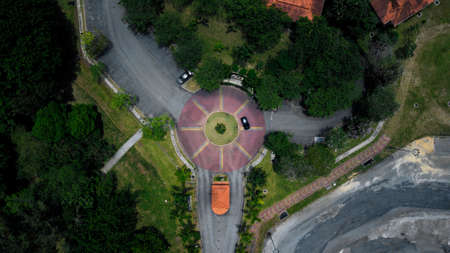 View from the top of a roundabout surrounded by trees in Malaysia leading into a park entrance
