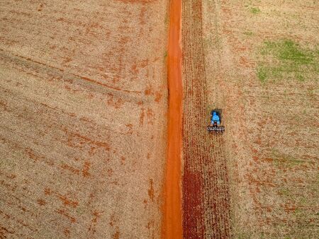 Aerial view of a tractor harrowing the soil to plant soybeans in Brazilの写真素材