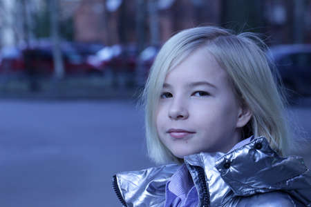 Closeup half-turned portrait of blonde little girl in modern grey jacket