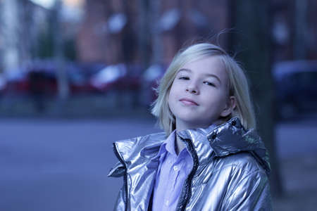Closeup half-turned portrait of blonde little girl in modern grey jacket