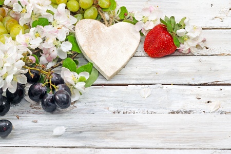 strawberry, grapes, heart and flowers on wooden table