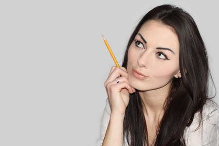 Portrait of a beautiful young woman standing against grey backgroundの写真素材