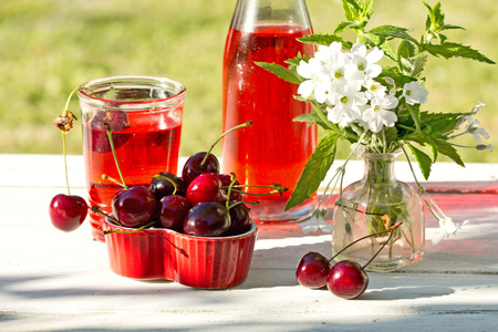 sweet cherries  in a heart box on wooden table in the gardenの写真素材