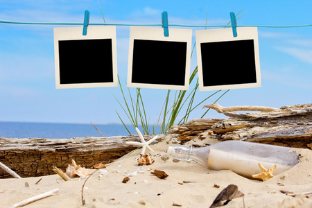 blank instant photos hanging on clothesline at the beachの写真素材