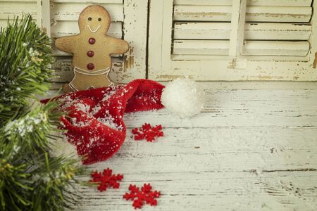 Christmas gingerbread with  red hat and snow on a wooden background
