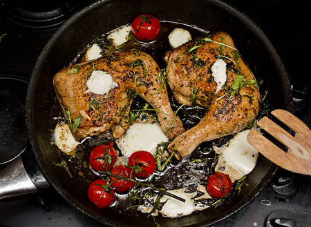 Roasted chicken legs with white cheese and tomatoesの写真素材