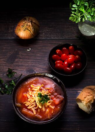 Tomato soup with noodles on a wooden table