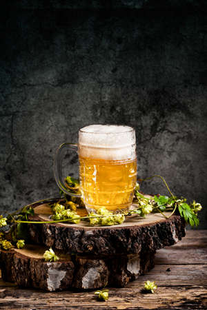 Beer mug with green hops and on a wooden tableの写真素材
