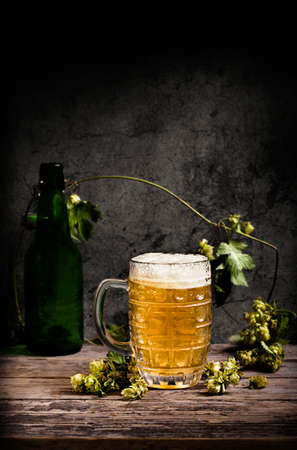 Beer mug with green hops and on a wooden tableの写真素材