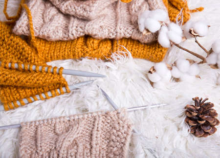 A piece of knitting with ball of yarn and a knitting needles. Knitting project in progress.