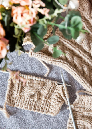 A piece of knitting with ball of yarn and a knitting needles. Knitting project in progress.の写真素材