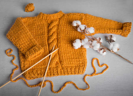 A piece of knitting with ball of yarn and a knitting needles. Knitting project in progress.
