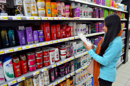 Portugal, Algarve, Monchique, Circa 10 December. 2013. Young woman selecting shampoo from a supermarket. Image taken on the 10th of December 2013 in Intermarche supermarket in the Algarve Portugal.のeditorial素材