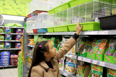 Portimao, Algarve, Portugal. 15 December 2013. Little girl looking at cages in a Pet product aisle...