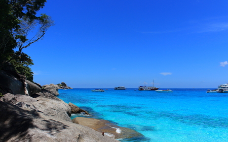 A paradise tropical landscape with idyllic bright azure clear water and the perfect blue sky. In the background in the transparent sea are high-speed boats. Classical representation of beach rest.の写真素材