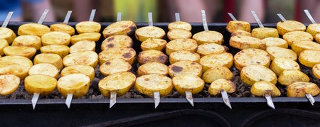 Fried potatoes on grill. Vegetarian tasty skewers from potatoes on charcoalの写真素材
