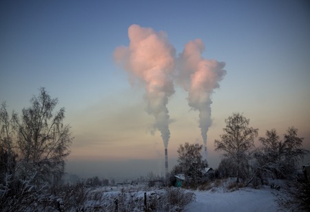 The pipes of the plant emits harmful substances into the atmosphere, creating a greenhouse effect. Winter landscape an dusk with heavy steam pipes and industrial fog. Concept pollution, smoke, ecologyの写真素材