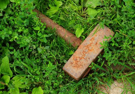 Close-up old heavy iron sledgehammer with a metal handle on green grass background.の写真素材