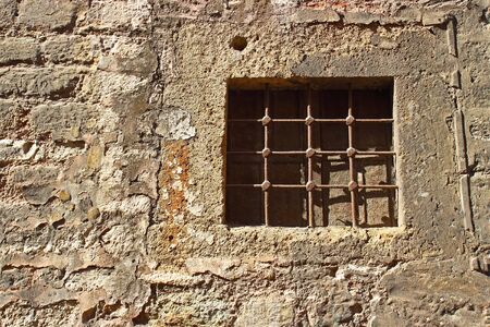 Closed window with rusty iron grate in ancient stone wall. Typical historic house in Istanbulの写真素材