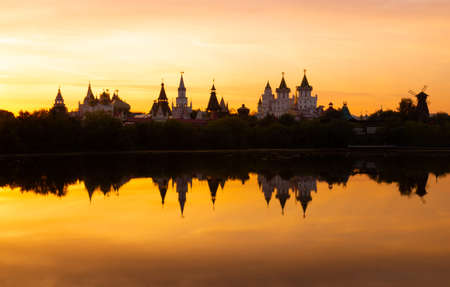 Awe orange sunset over blurry reflection of the Izmailovsky Kremlin in the lake water at Moscow, Russia. Russian landscape in warm colorsの写真素材