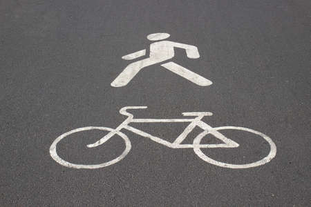 White road markings on pavement. Signs of pedestrian and bike on the asphalt. Sidewalk for...