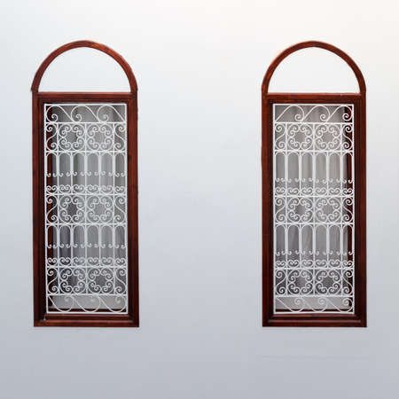 Two narrow windows decorated with decorative lattice on a white plastered wall. Moroccan authentic interior traditional for medina quarter at Marrakeshの写真素材