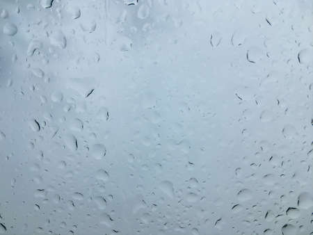 Water drops on glass surface. Wet window after rain. Abstract background in gray tonesの写真素材