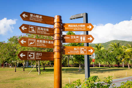 China, Hainan island, Sanya - January 23, 2020: Bright wooden street pillar with arrows showing...