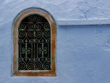 Old decorative lattice in plastered blue wall. Typical house in the medina of Hammamet town, Tunis. House details in North Africaの写真素材