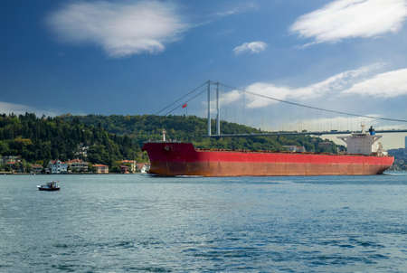 Large cargo ship passing under the bridge in Bosphorus Strait in Istanbul, Turkeyの写真素材