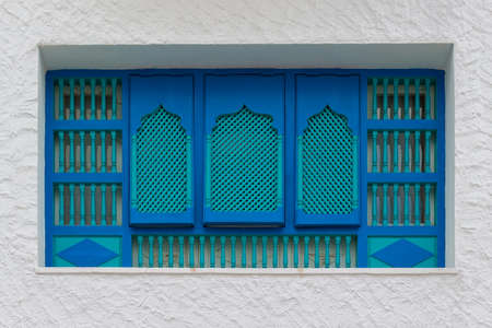Tunisian turquoise slatted wooden shutters on windows at plastered wallの写真素材