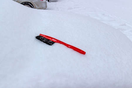 Brush for cleaning snow lies on car buried fluffy snow