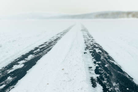 Ice road across frozen lake. Car trail on surface of the natural ice. Winter landscape in Siberia, Russiaの写真素材