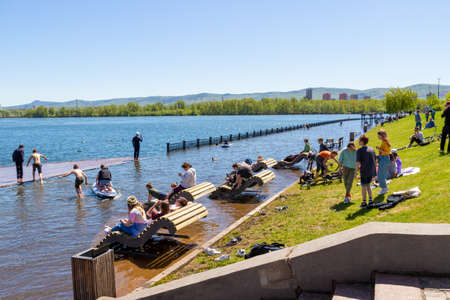 Krasnoyarsk, Russia - June 1, 2021: careless people rest on the flooded city embankment. Flooding of Yenisei River in spring during melting a lot of snow. Natural disasterのeditorial素材