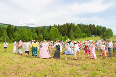 Krasnoyarsk, Russia - June 19, 2021: People holding hands drive a round dance during the celebration of a traditional Slavic holiday of Ivan Kupala. Men and women are dancing around a fire on meadowのeditorial素材