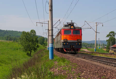 Red old freight train or locomotive on Trans-Siberian Railway along Russian village in Siberia
