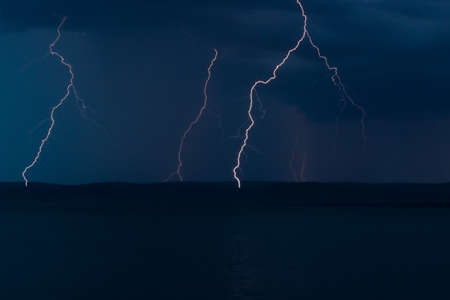 Thunderstorm with lightning bolts strikes in night stormy sky